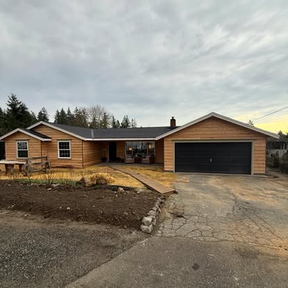 Ranch home exterior before remodel — raw cedar siding and unfinished yard