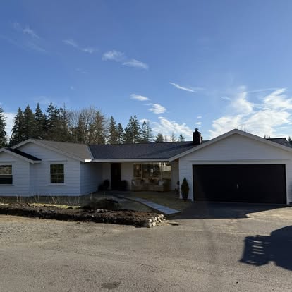 Same ranch home after remodel — finished white siding and clean driveway