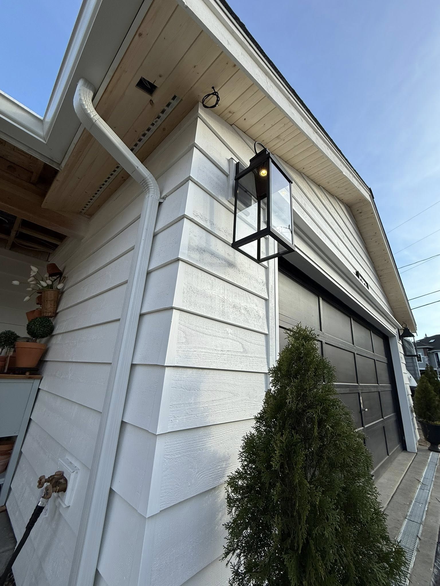 Custom white lap siding with black exterior sconce and cedar soffit detail